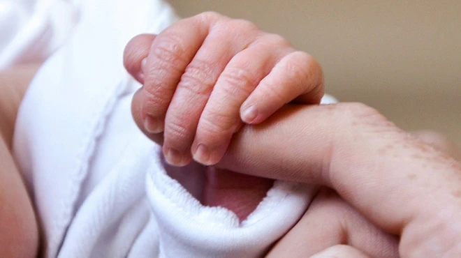 Baby's hand holding parent's finger