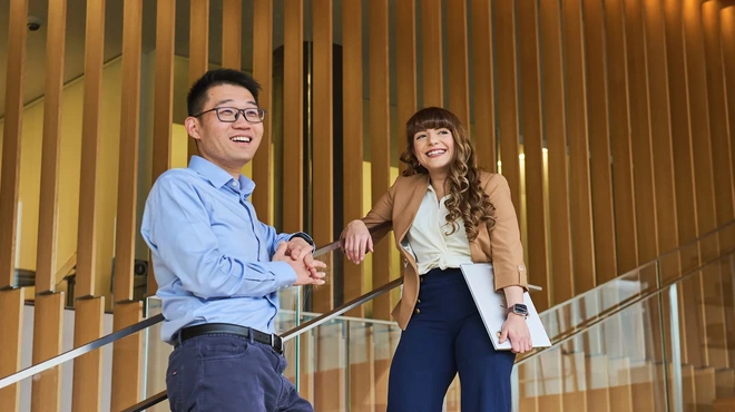 Two business people on stairs smiling